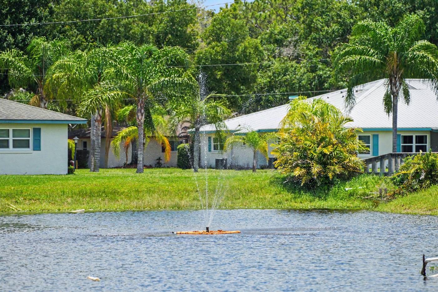 Homes with blue trim across the lake, fountain in front